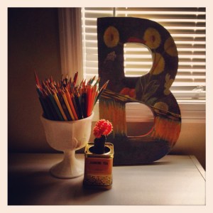 This last step may be the most important.  Remember, social media was invented so that you can show other people that you’re better than them, or at least that you’re stable enough to do crafts, even if you’ve worn your pajamas with a chunky bracelet and a fashionable belt for three months straight.  Therefore, it is essential to photograph your craft and show it to as many people on the Internet as possible.  Otherwise, what’s the point?  Oh, that’s right.  NONE.  There is NO POINT.  Find the one surface in your house that doesn’t look like it’s part of a still from Grey Gardens and set your craft up there.  You’ll need to arrange a little vignette by placing other objects near the craft.  Make sure that they’re kind of vintage-y and used in witty and unexpected ways, like this milk glass hand-me-down filled with colored pencils, or a Mason jar sippy-cup filled with wine coolers.